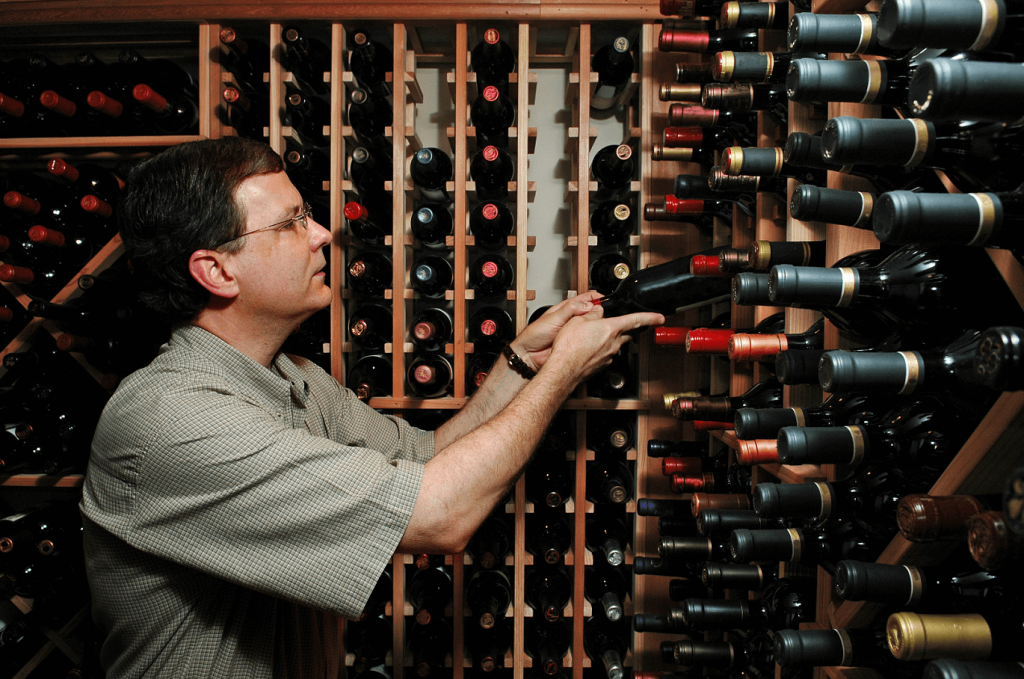 Homme qui regarde les bouteilles de vins dans une cave à vin